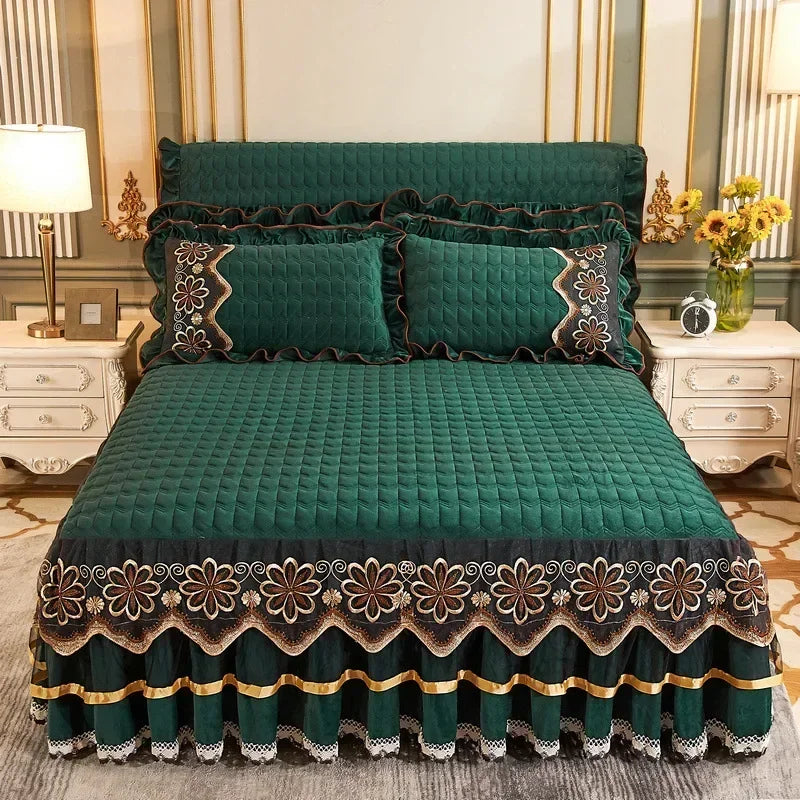 Emerald green velvet bed skirt with gold embroidery and ruffled hem on a bed.