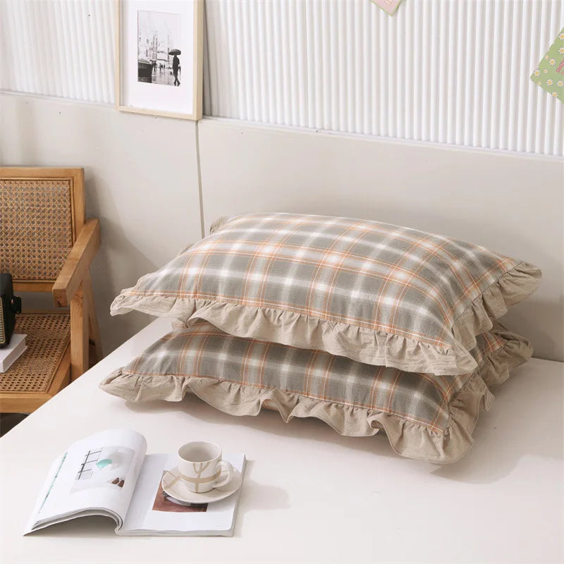 A set of two soft plaid washed cotton pillowcases with ruffled edges displayed on a white surface.