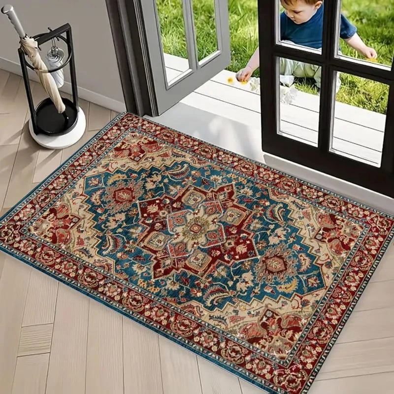 A rectangular retro floral area rug with blue, red, and beige patterns placed on a light wood floor near a glass door.