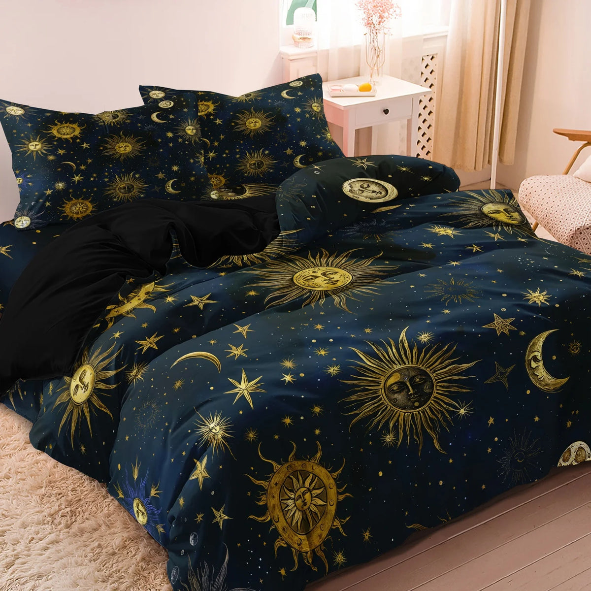 A dark blue duvet set featuring a gold sun and moon pattern with stars on a light pink background.