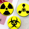Three yellow circular pins featuring black radiation symbols on a white background.
