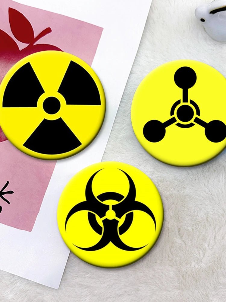 Three yellow circular pins featuring black radiation symbols on a white background.