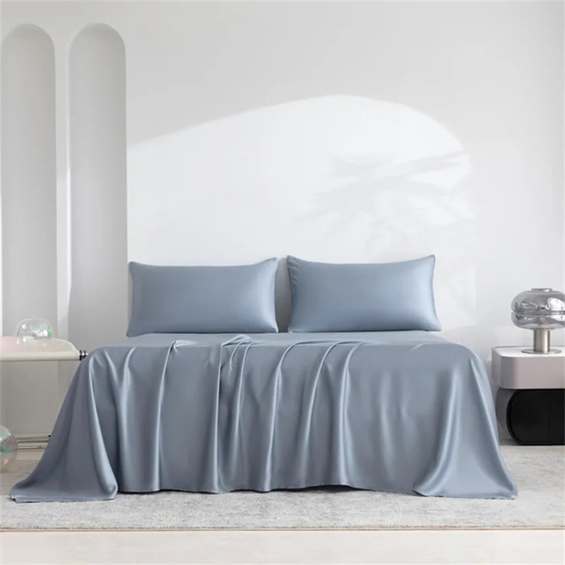 A light blue luxury organic bamboo bed sheet set draped on a bed with white walls and natural light.