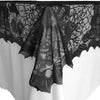 Black spider web lace table runner displayed on a white tablecloth.