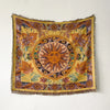 A richly colored bohemian geometric throw blanket featuring sun motifs and floral patterns on a yellow background.