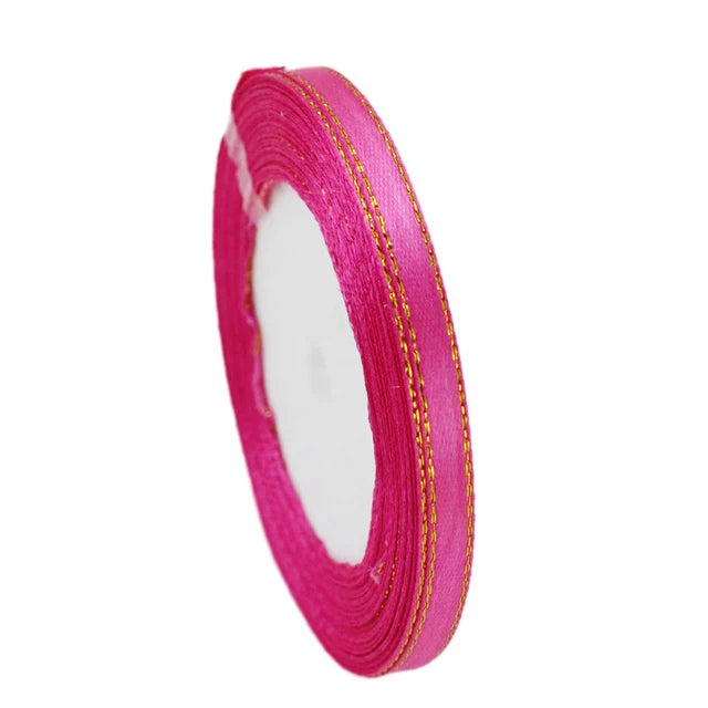 Roll of 6mm gold-edged satin ribbon in bright pink for gift wrapping and crafts
