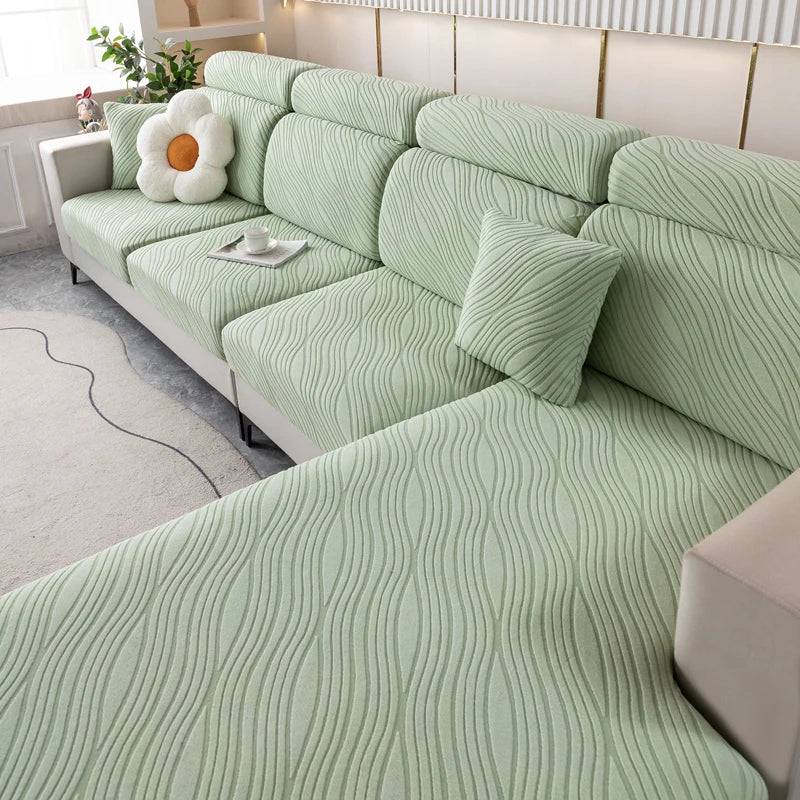 A light green plush elastic sofa cushion cover with a wavy texture and white decorative pillows.