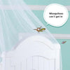 A mosquito is shown flying near a white crib with a sheer netting draped over it.