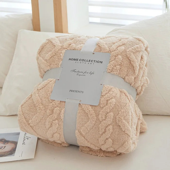 A fluffy, light beige throw blanket with a diamond pattern is presented in a square gift box.