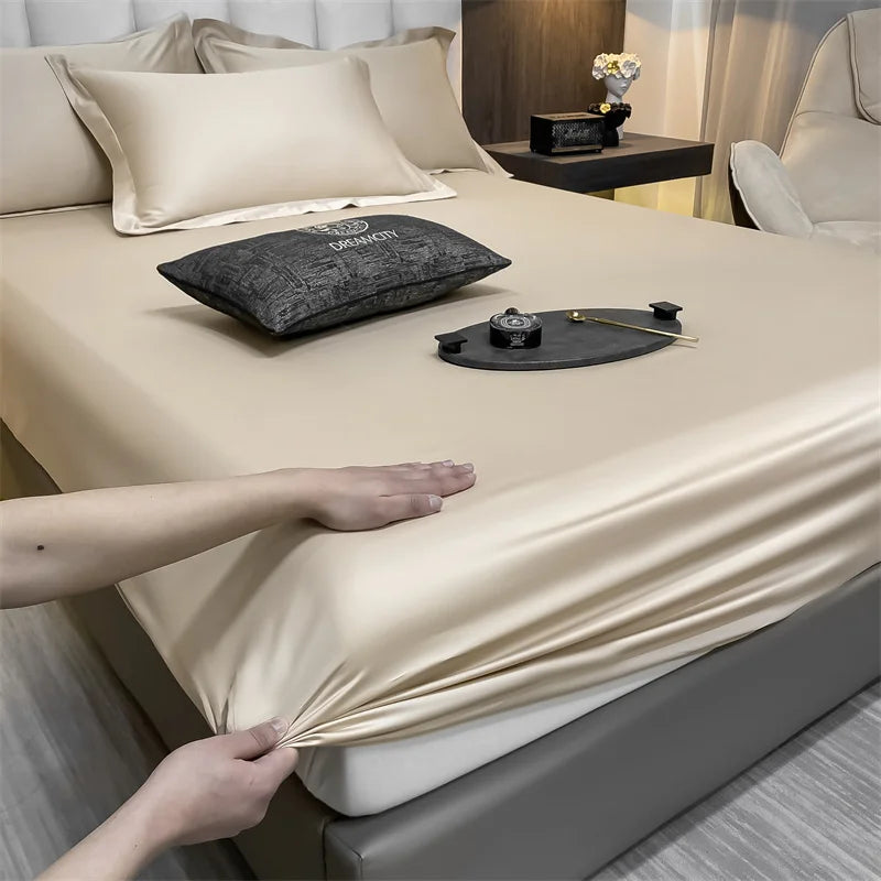 A close-up of a luxury Egyptian cotton fitted bed sheet being adjusted on a beige bed.