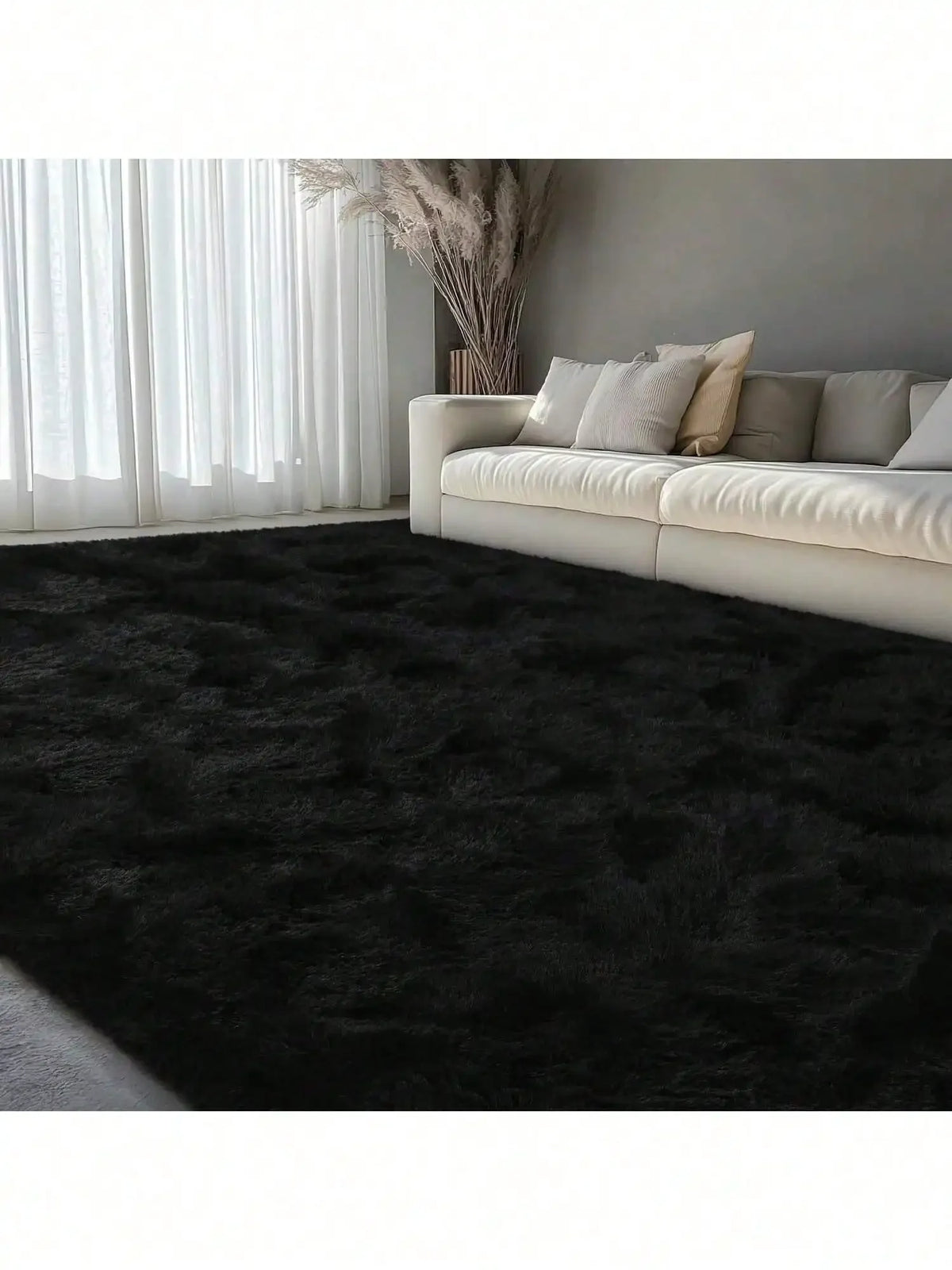 A dark gray plush long-pile area rug placed in a modern living room with sheer white curtains and a light sofa.