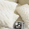 A close-up of a white jacquard plush throw pillow cover with a geometric quilted pattern.