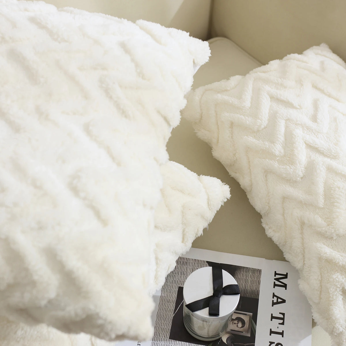 A close-up of a white jacquard plush throw pillow cover with a geometric quilted pattern.