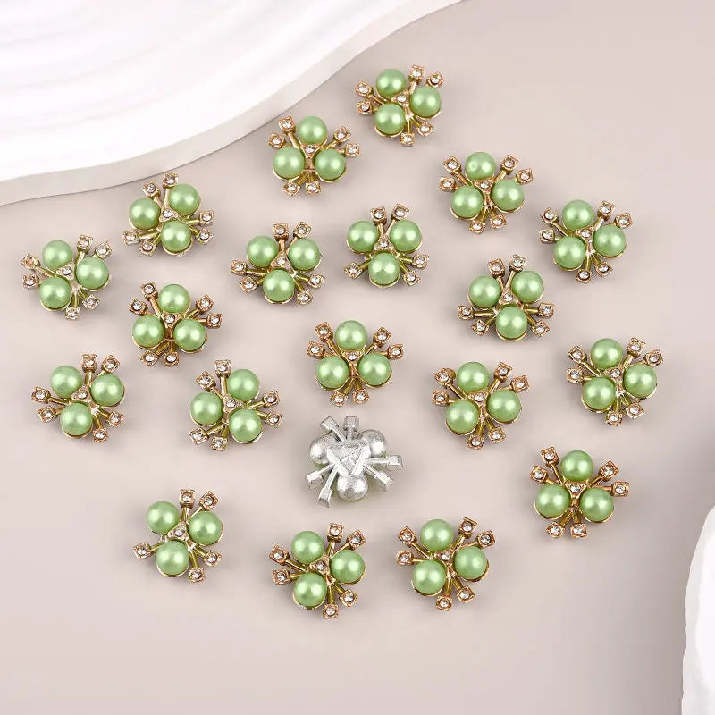 A set of flower-shaped resin button rhinestones in light green and gold tones.