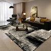 A black and white geometric non-slip area rug is displayed in a modern living room setting.