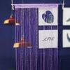 Purple beaded string curtains hanging, featuring a white heart design and the word LIVE.