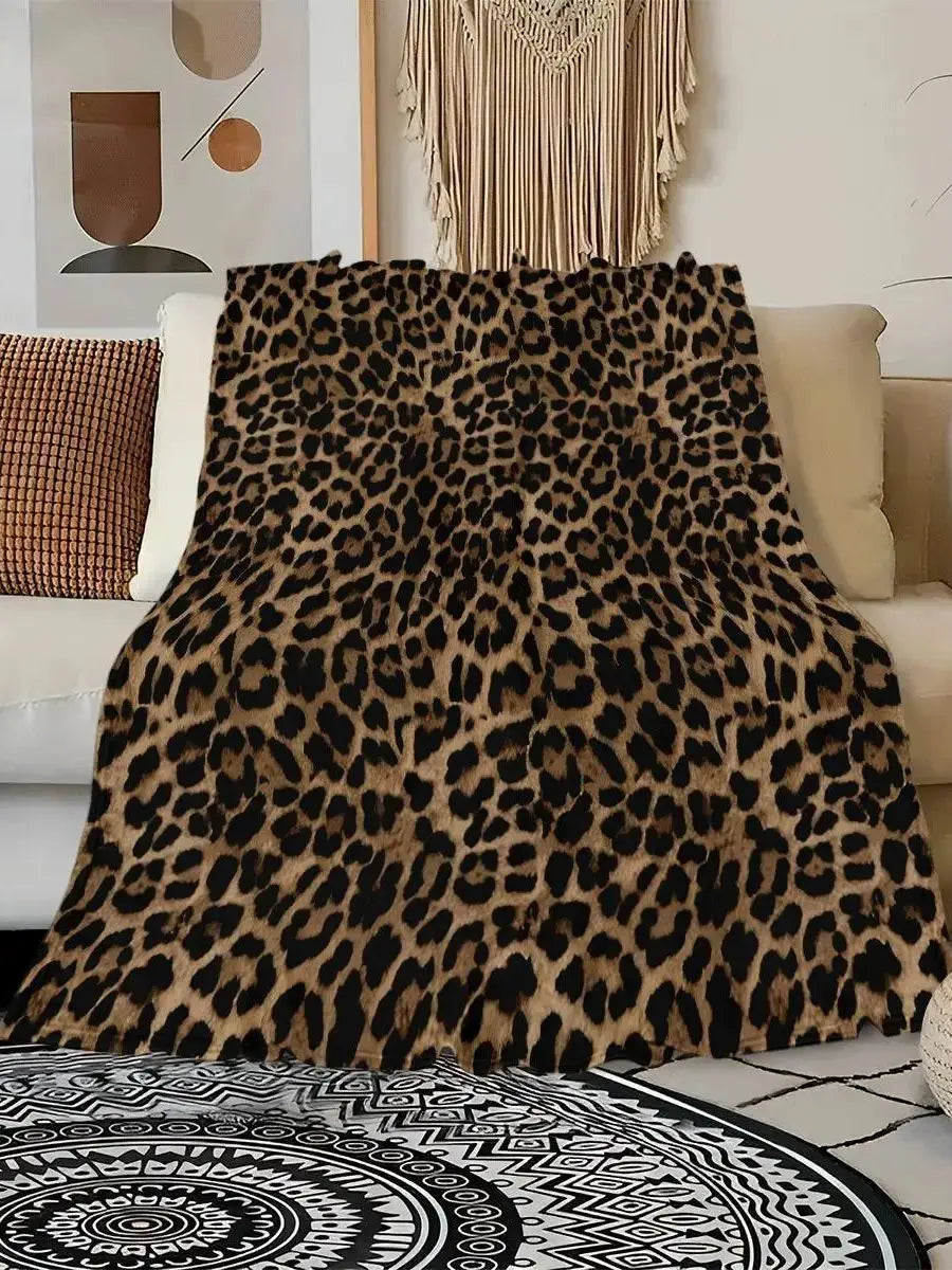 A luxurious leopard print flannel blanket draped over a light-colored sofa.