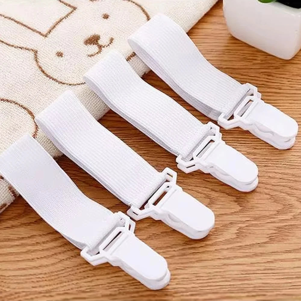 A set of white adjustable bed sheet and quilt holders lying on a wooden surface.