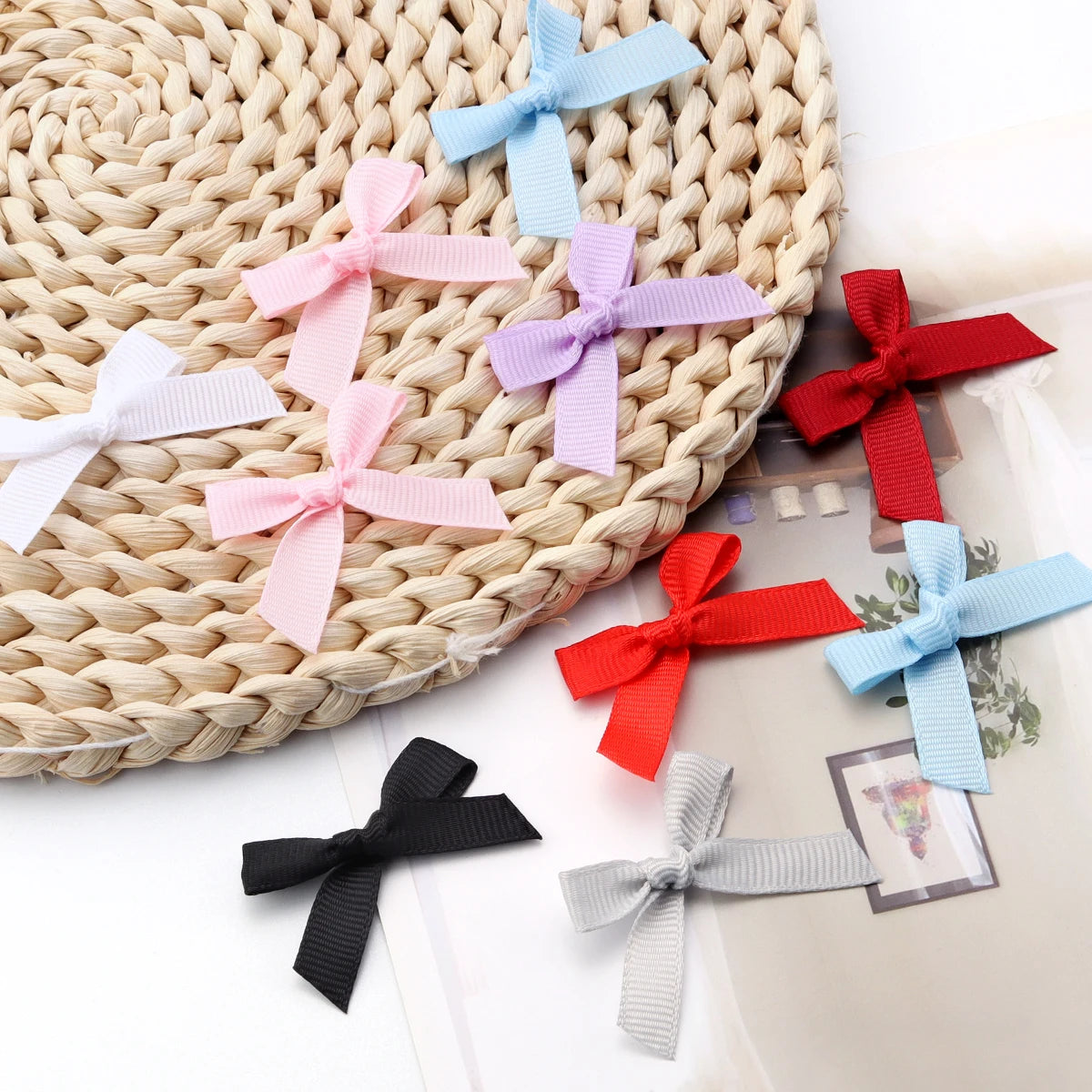 A collection of satin ribbon bows in various pastel colors including pink, blue, purple, and red arranged on a woven mat.