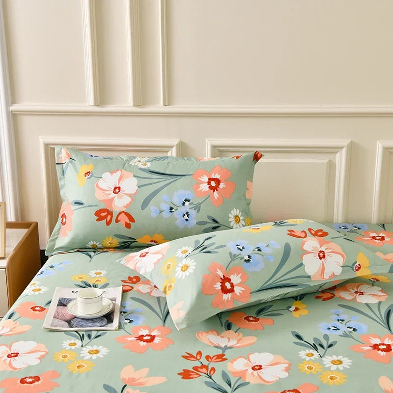A floral fitted sheet set with pillowcases featuring pink, orange, and blue flowers on a light green background.