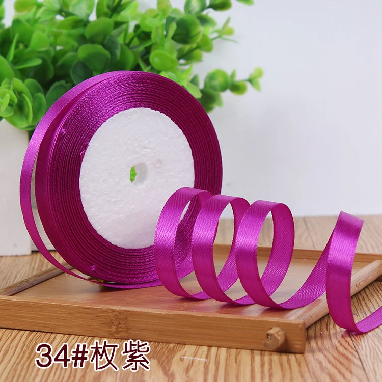 Roll of vibrant magenta satin ribbon used for crafting or decoration