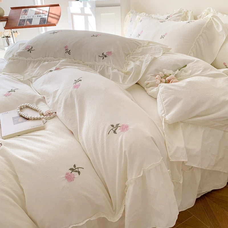 White duvet cover set with pink embroidered roses on a bed