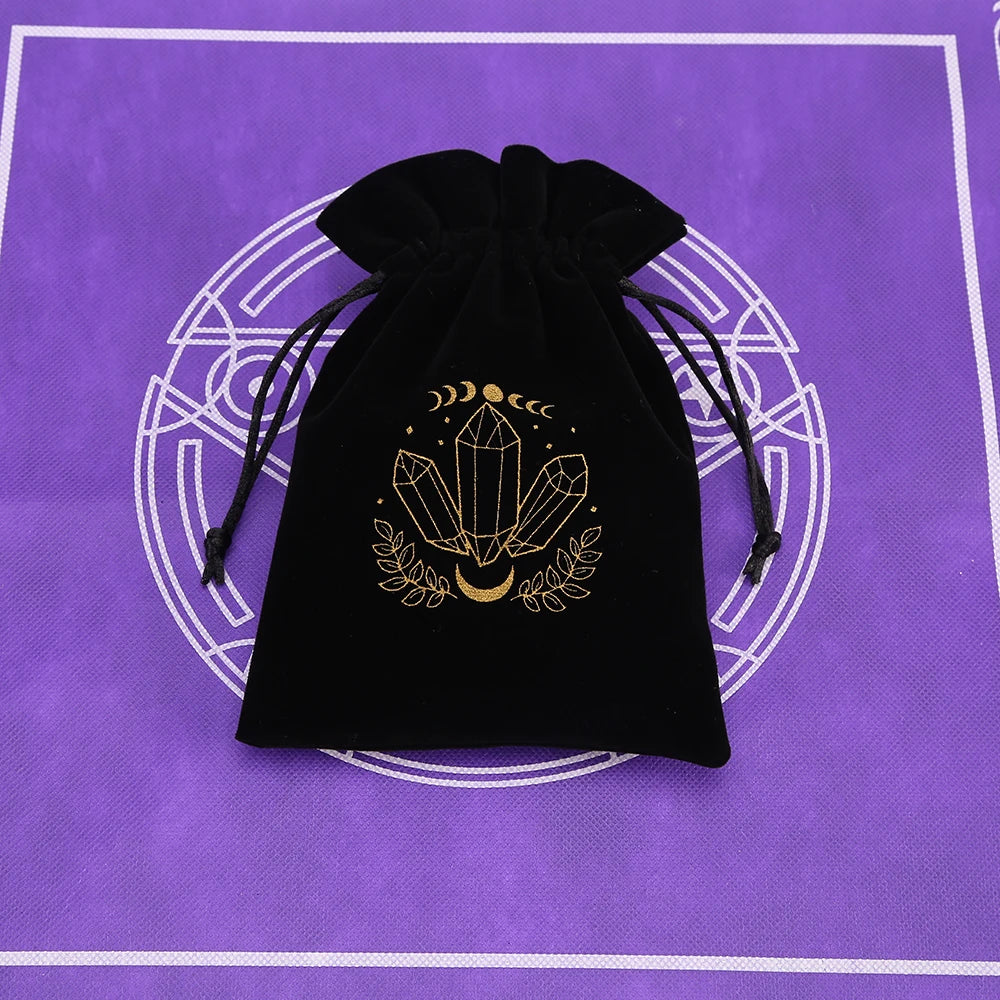 A black velvet pouch with gold crescent moon and crystal symbols is displayed on a purple patterned surface.