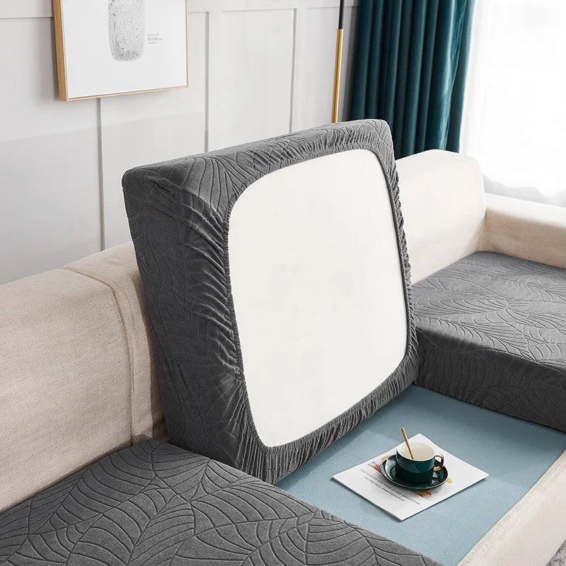 A gray waterproof jacquard stretch sofa cover is displayed on a light-colored sofa.
