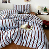 A bed dressed with a striped blue and brown duvet cover set and matching pillowcases.