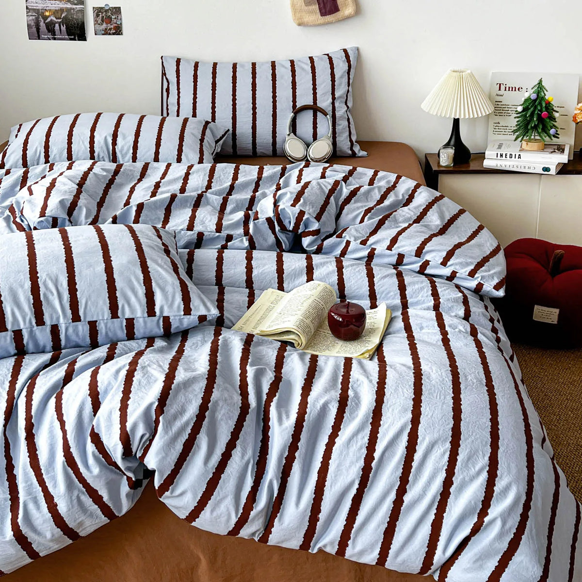 A bed dressed with a striped blue and brown duvet cover set and matching pillowcases.