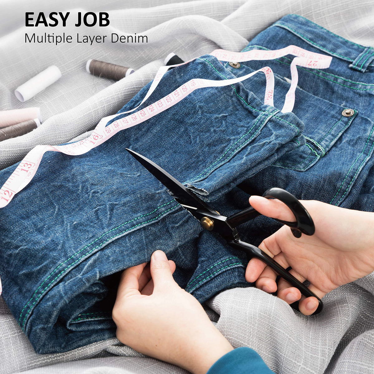 Hands are using heavy duty industrial tailor scissors to sew multiple layer denim fabric.