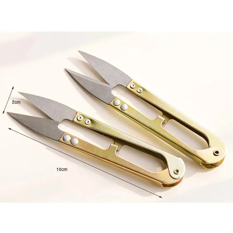 A pair of gold-toned U-shape sewing scissors with silver blades shown on a white background.