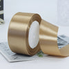 Roll of satin craft ribbon in a gold color with white filling shown on a white surface.