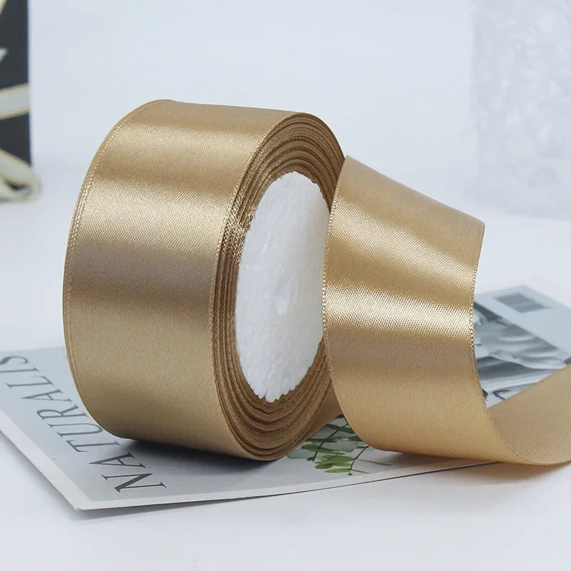 Roll of satin craft ribbon in a gold color with white filling shown on a white surface.