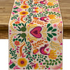 A linen table runner featuring a vibrant floral pattern in shades of pink, yellow, orange, and green.