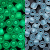 A close-up view of green and blue glow-in-the-dark glass seed beads in various sizes