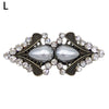 Vintage swirl clip brooch featuring a silver-toned oval stone surrounded by clear rhinestones and dark filigree detailing.