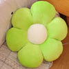 A bright lime green sunflower plush flower cushion with a white center resting on a light-colored fabric.