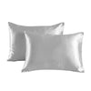 A pair of smooth, light gray satin pillowcases lying flat.