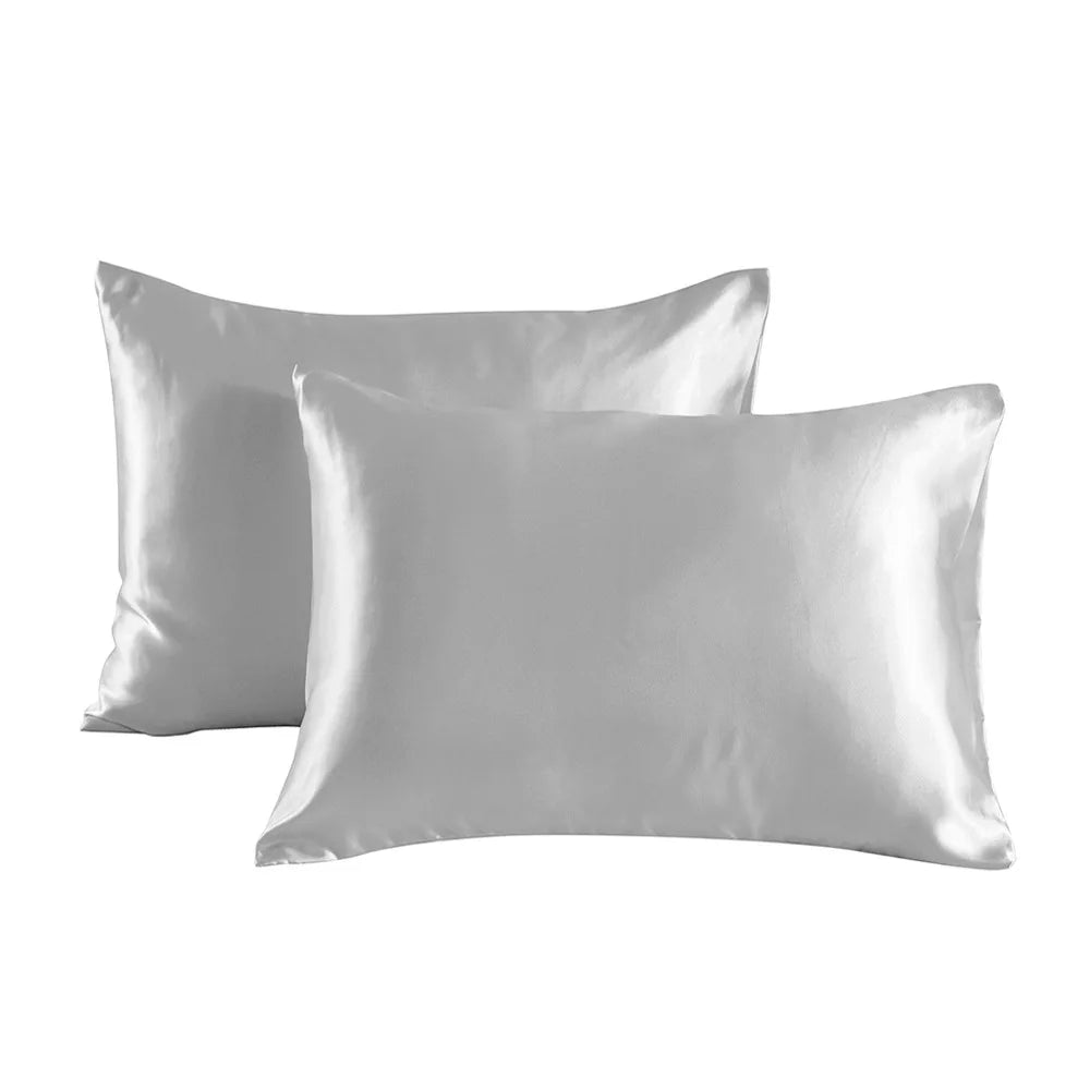 A pair of smooth, light gray satin pillowcases lying flat.