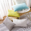 A collection of textured throw pillows in pastel blue, yellow, gray, and white resting on a gold-toned wire tray.
