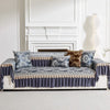 A navy blue quilted sofa cover with lace trim and patterned pillows displayed in a bright room.