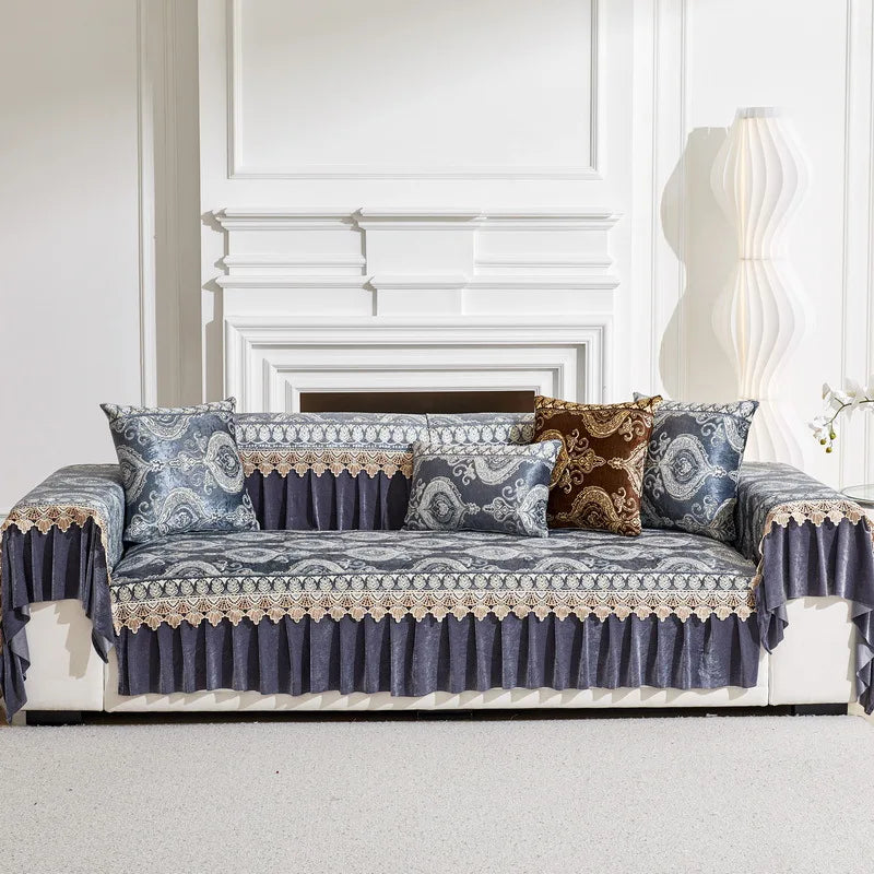 A navy blue quilted sofa cover with lace trim and patterned pillows displayed in a bright room.