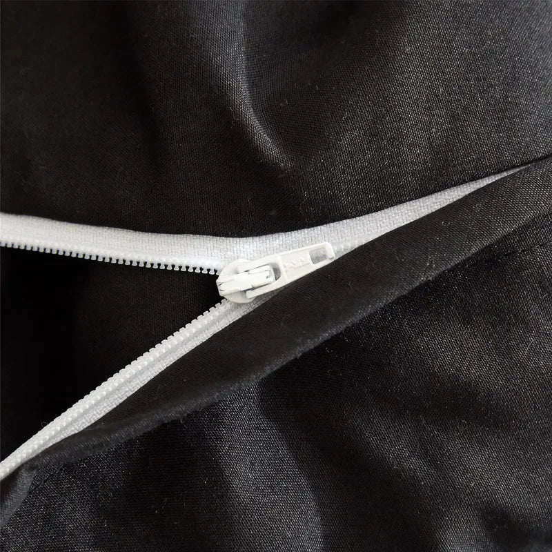Close-up of a black duvet cover with a silver zipper detail.