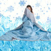 A woman is wrapped in a light blue quilted blanket with snowflake patterns against a snowy background.