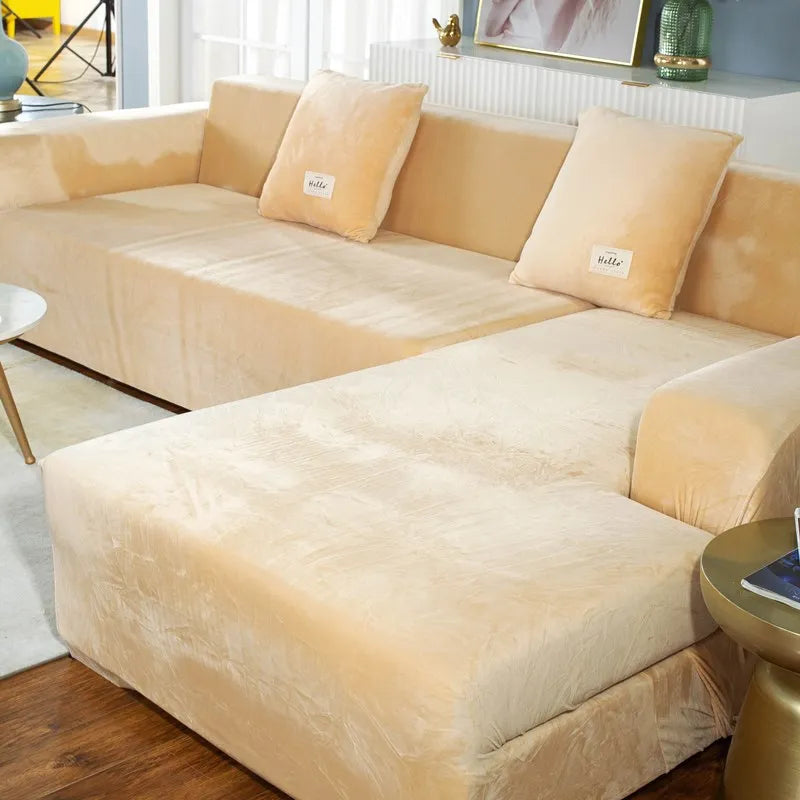 A light beige velvet sofa cover for an L-shaped sectional sofa with throw pillows.