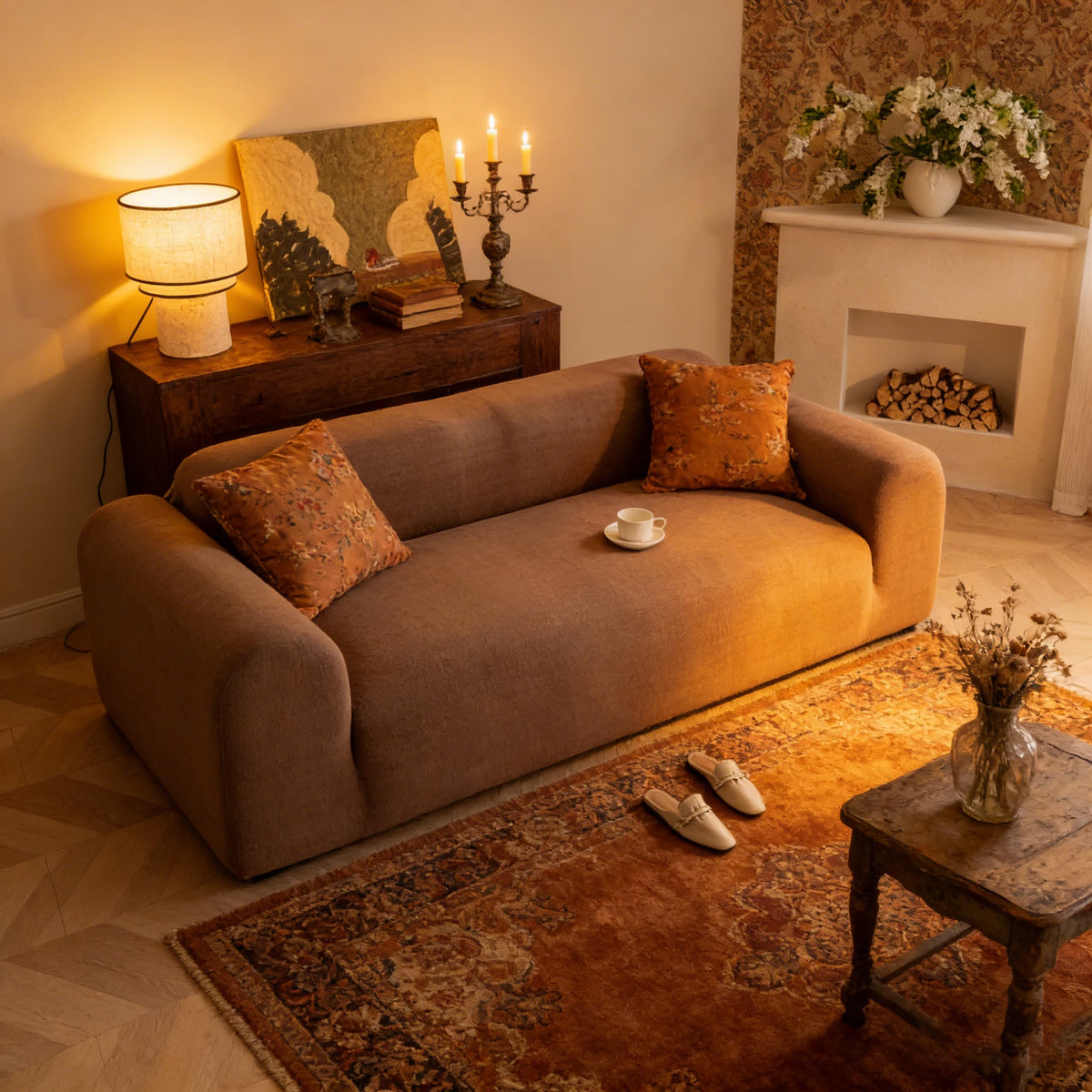 A comfortable, tan quilted sofa is shown in a warmly lit living room with an orange rug and decorative elements.