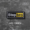 Black embroidered badge with yellow text Stepbro on a dark gray textured background