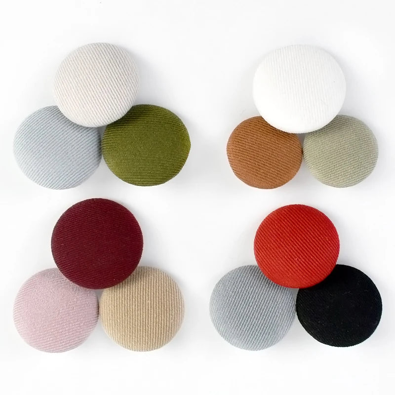 A set of round fabric-covered shank buttons in various shades of beige, green, gray, and terracotta.