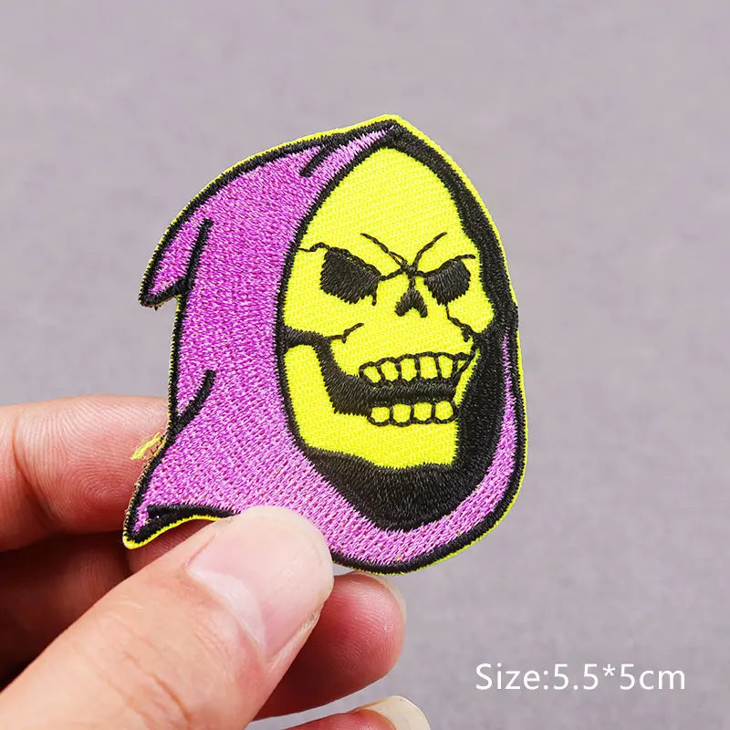 A purple and yellow embroidered patch featuring a stylized skull face.